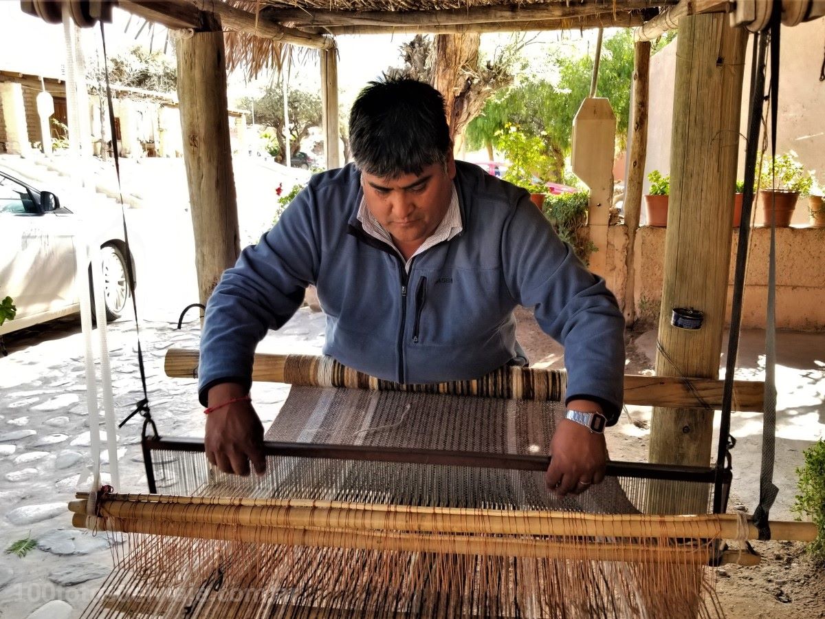 Man weaving on a loom outdoors with a casual setting