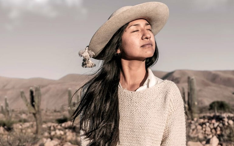 Woman wearing a beige hat and sweater in a desert landscape